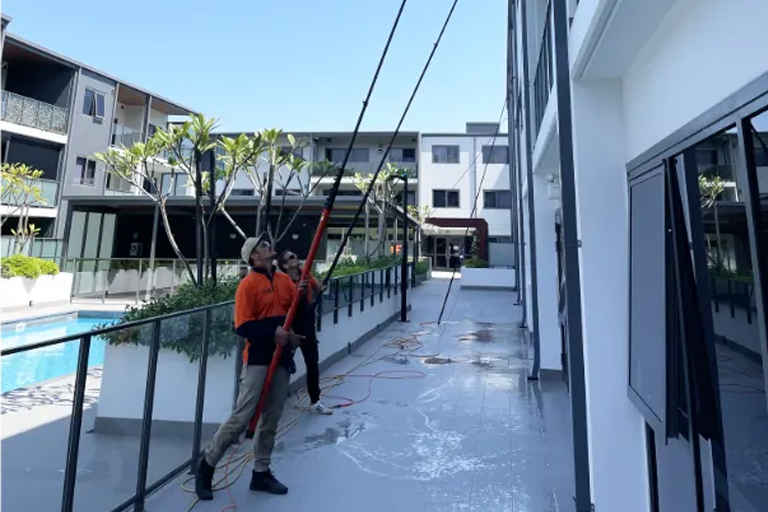 Three rope access technicians clean the glass windows of a high-rise building.