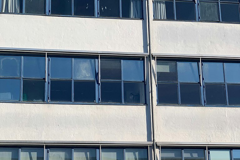 A modern glass building reflecting the sky and clouds, highlighting the need for high-rise window cleaning.