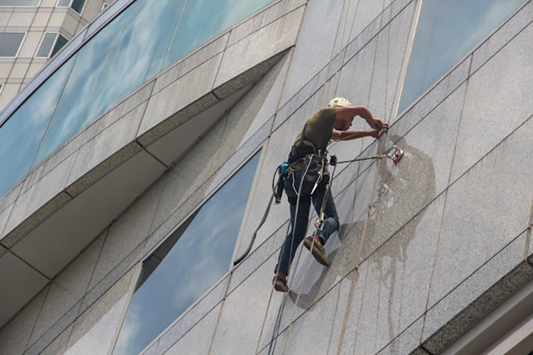 A rope access technician cleans the windows of a high-rise building.