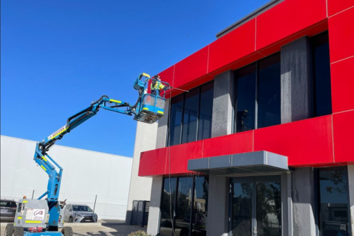 A Starbucks storefront with a large metal logo and illuminated signage on a wooden-paneled exterior, requiring cleaning for maintenance and upkeep.