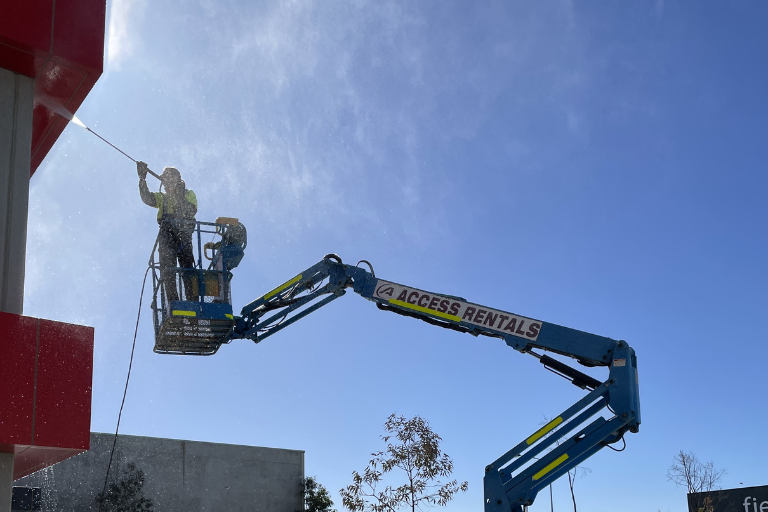 A rope access technician cleans the windows of a high-rise building.