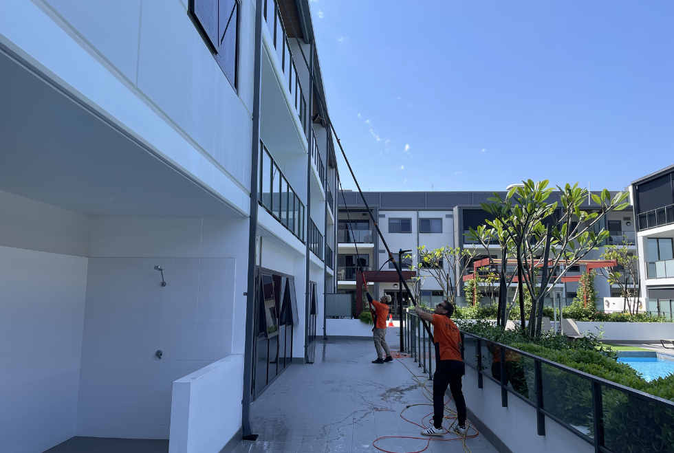 Modern high-rise buildings with glass facades towering against a clear blue sky, requiring rope access cleaning for exterior maintenance.